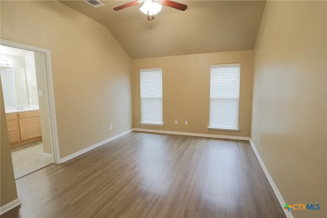 an empty room with wooden floor chandelier fan and windows