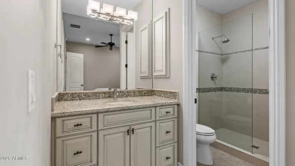a bathroom with a granite countertop sink a toilet and shower