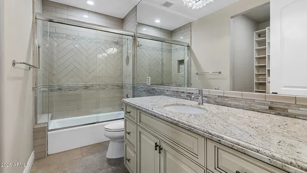 a bathroom with a granite countertop sink a toilet and shower