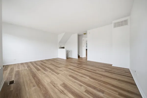 a view of empty room with wooden floor