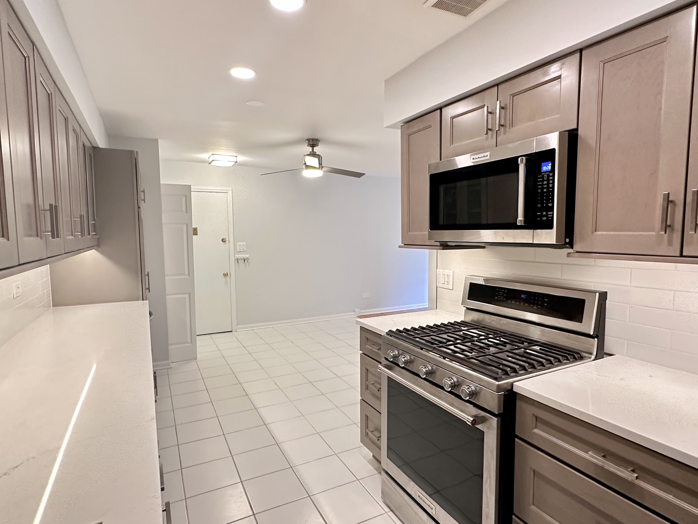 1603 North Windsor Drive, Unit 102 Arlington Heights, IL 60004 - Photo 8 of 18 a kitchen with stainless steel appliances a stove a microwave and white cabinets