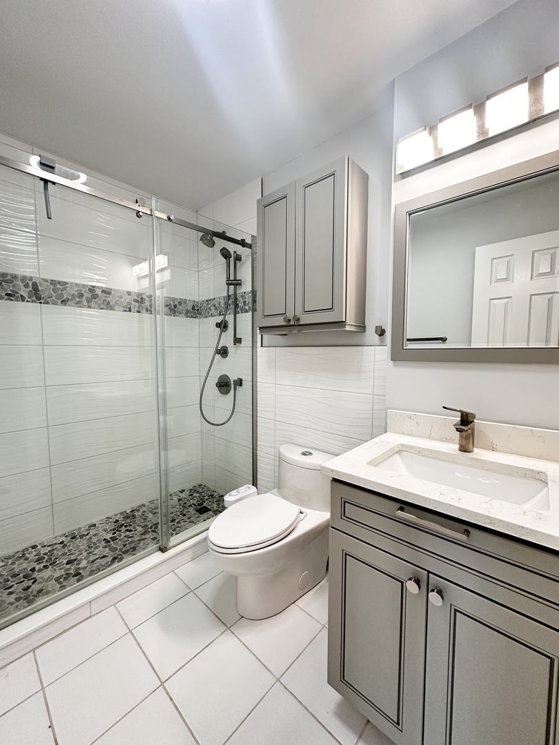 1603 North Windsor Drive, Unit 102 Arlington Heights, IL 60004 - Photo 9 of 18 a bathroom with a granite countertop sink a toilet a mirror and shower