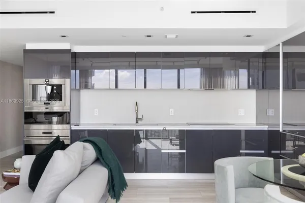 a living room with stainless steel appliances kitchen island granite countertop a couch chair and a view of kitchen
