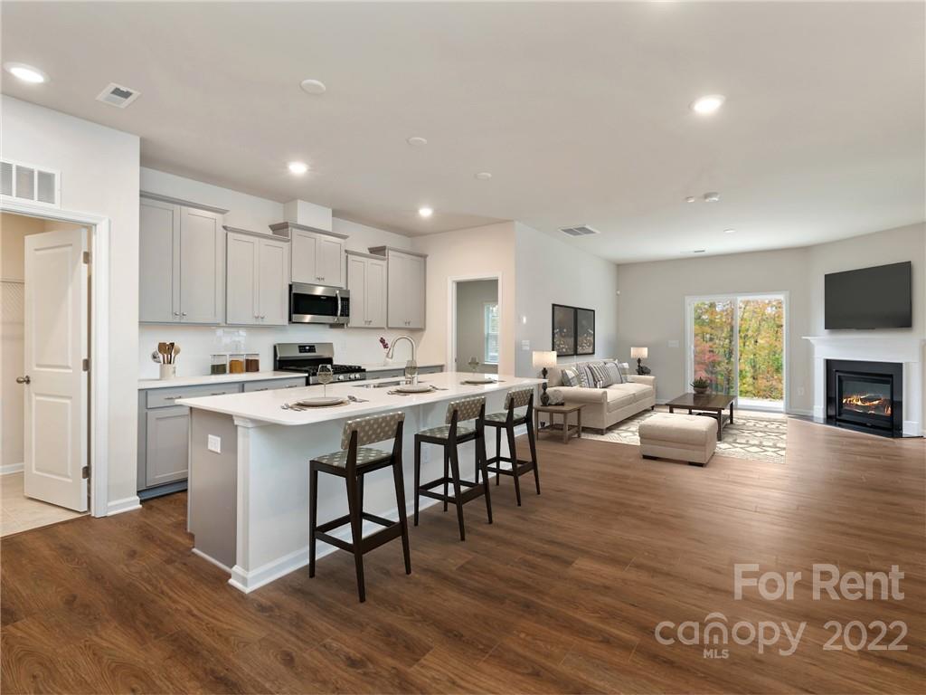 6531 Gopher Road Lancaster, SC 29720 - Photo 7 of 29 a living room with stainless steel appliances kitchen island granite countertop a couch a dining table and chairs with wooden floor
