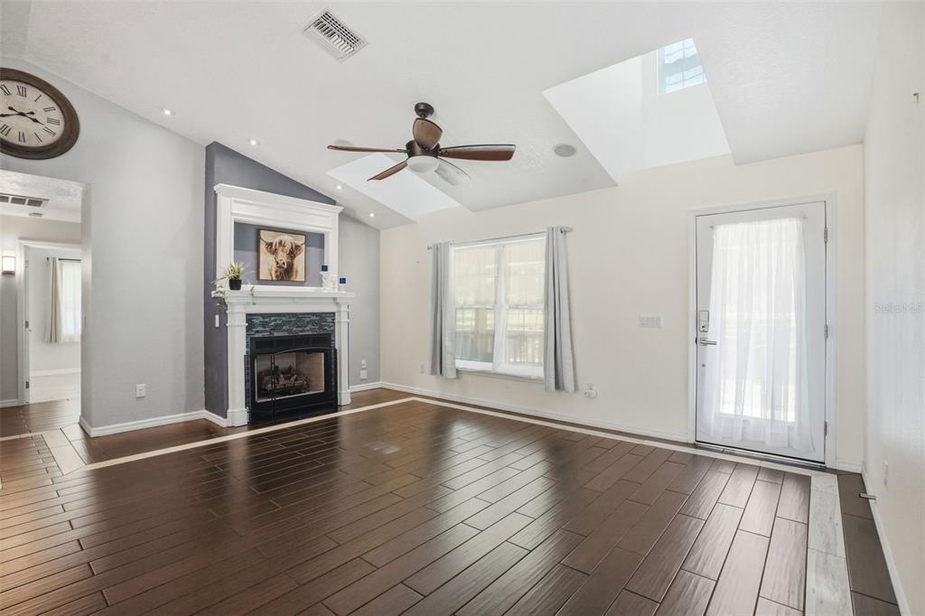 7037 County Road 625 Bushnell, FL 33513 - Photo 23 of 99 an empty room with windows a fireplace a ceiling fan and wooden floor