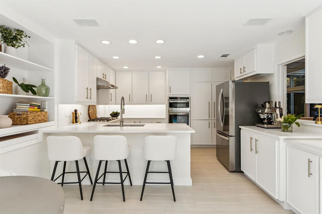 9616 Viewside Drive Dallas, TX 75231 - Photo 14 of 38 Kitchen featuring white cabinetry, open shelves, appliances with stainless steel finishes, recessed lighting, and a kitchen bar