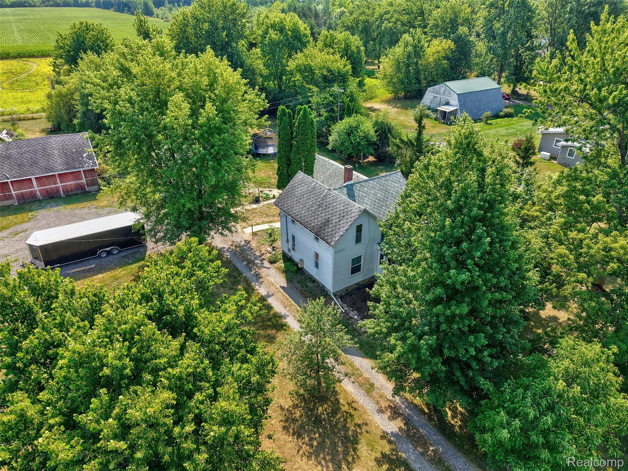 1175 South Morrish Road Flint, MI 48532 - Photo 62 of 72 Aerial view of a property featuring a light-colored main residence with a dark shingle roof, a red barn with a dark roof, and a gray barn with a green roof