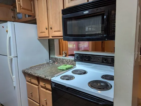 a white refrigerator freezer and a stove sitting inside of a kitchen