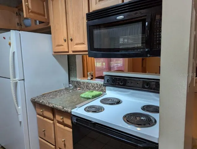 a white refrigerator freezer and a stove sitting inside of a kitchen