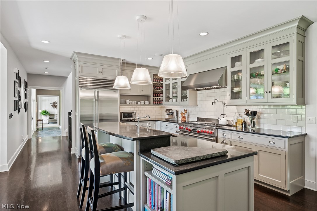 The kitchen offers plenty of closed storage, glass front display cabinets and open shelves.