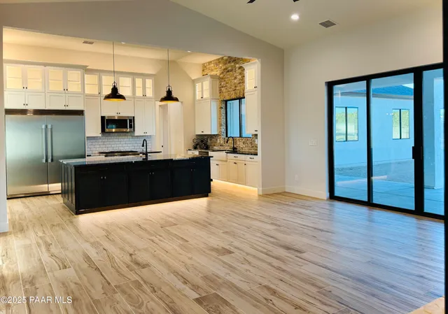 a view of kitchen with stainless steel appliances granite countertop a sink and cabinets with wooden floor