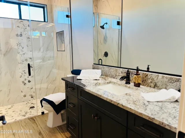 a bathroom with a granite countertop sink a toilet and shower