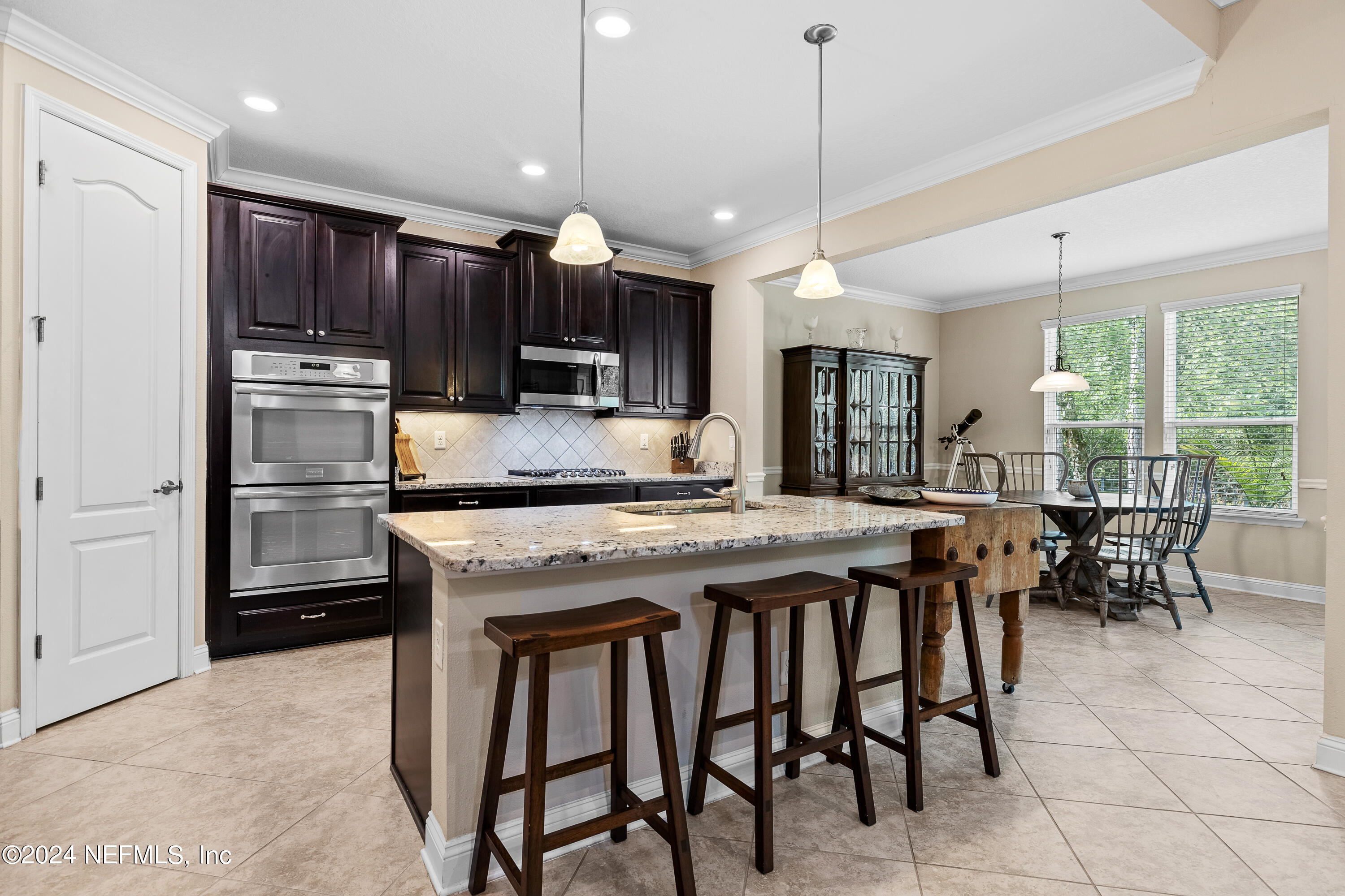 405 St Kitts Loop St. Augustine, FL 32092 - Photo 16 of 65 a kitchen with stainless steel appliances granite countertop a stove a refrigerator a oven a sink with a dining table and chairs