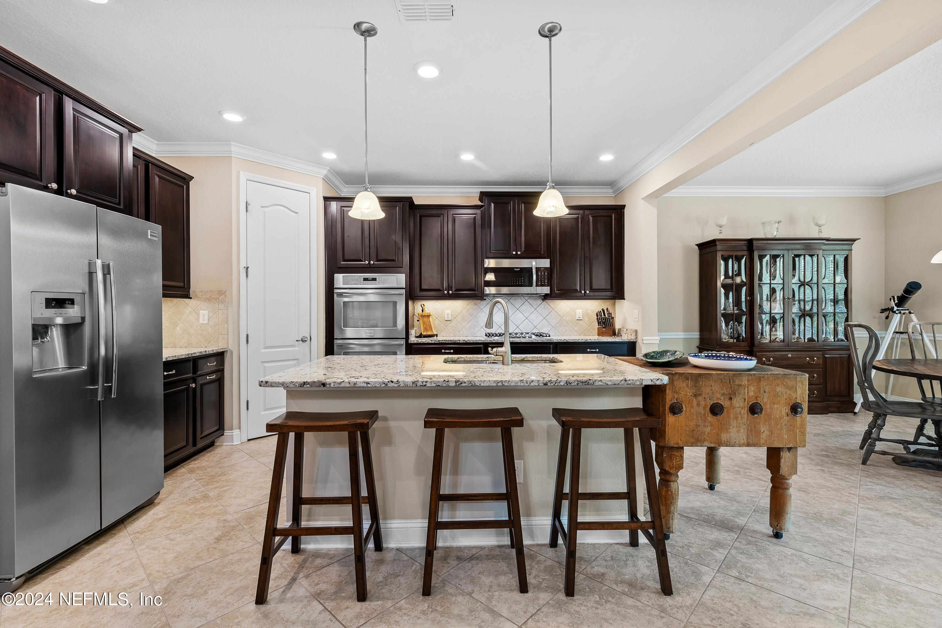 405 St Kitts Loop St. Augustine, FL 32092 - Photo 17 of 65 a kitchen with stainless steel appliances granite countertop a kitchen island a stove a refrigerator a oven a sink with a dining table and chairs