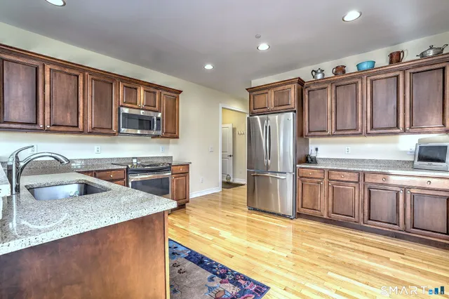 a kitchen with stainless steel appliances granite countertop a refrigerator stove top oven and sink
