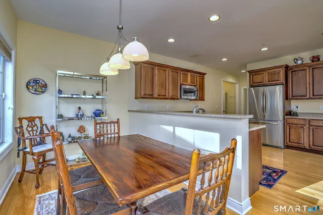 a kitchen with stainless steel appliances granite countertop a stove a sink a dining table and chairs with wooden floor