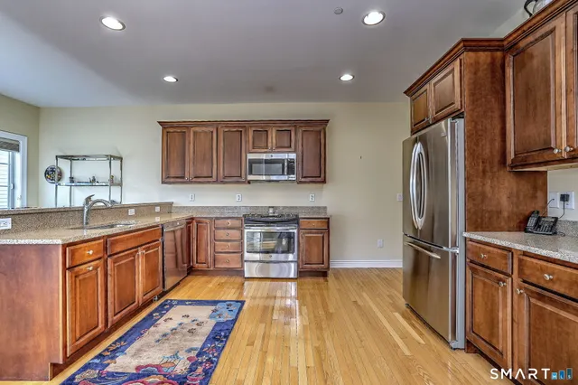 a kitchen with stainless steel appliances granite countertop a refrigerator stove top oven and sink