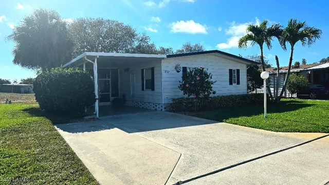a front view of house with yard and trees in the background