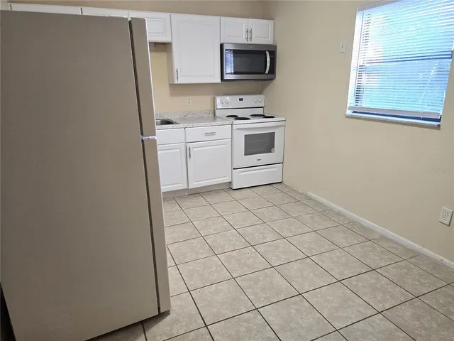 a kitchen with white cabinets a sink and white appliances