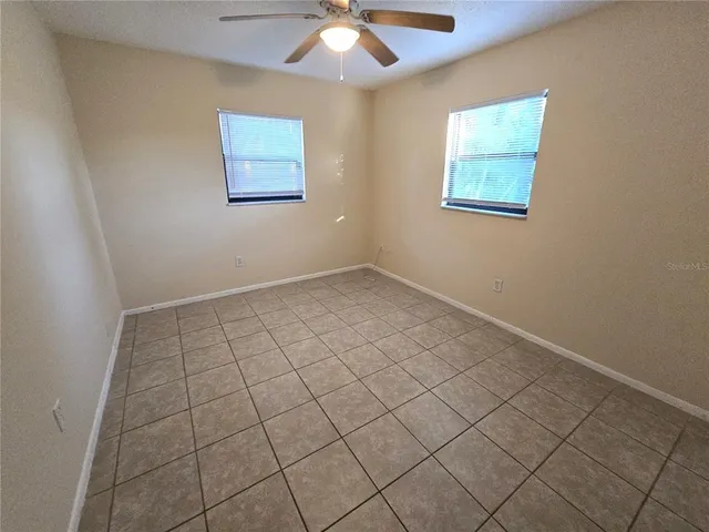 an empty room with windows and fan