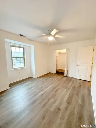 a view of empty room with wooden floor and fan