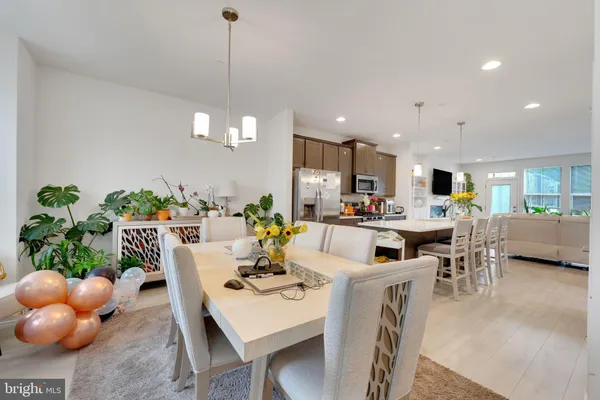 a dining room with furniture a potted plant and kitchen view