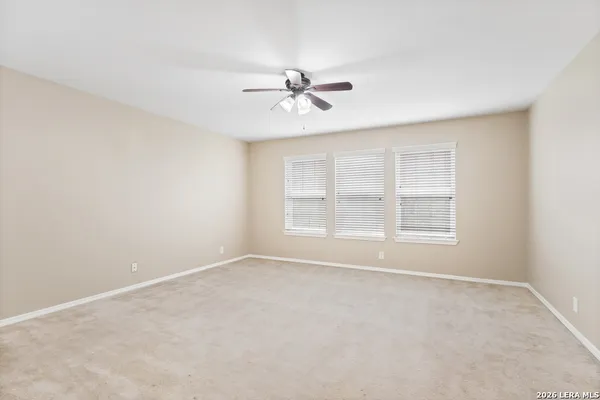 an empty room with chandelier fan and windows