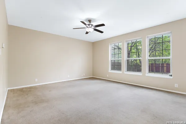 an empty room with chandelier fan and windows
