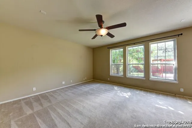 a view of empty room with window and ceiling fan
