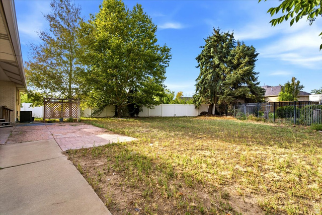 2455 South Bluff Road Syracuse, UT 84075 - Photo 28 of 32 Spacious backyard with mature trees, concrete patio, and fenced perimeter