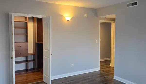 an empty room with wooden floor closet and windows