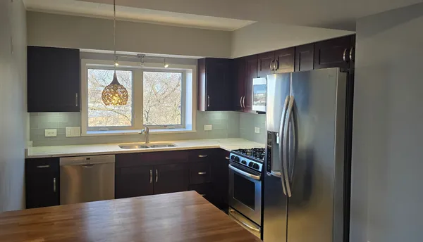 a kitchen with stainless steel appliances granite countertop a refrigerator a sink a stove and island