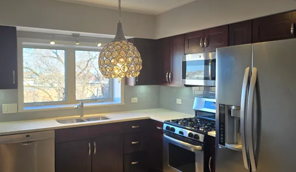 a kitchen with stainless steel appliances granite countertop a sink a stove a refrigerator and a window