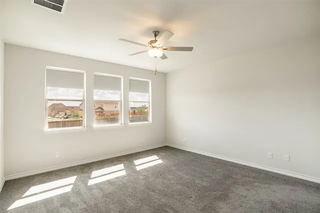 an empty room with windows and fan