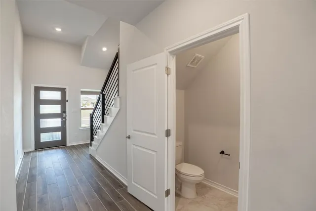 a bathroom with a toilet and a wooden floor