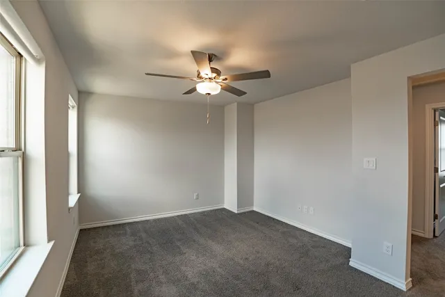 an empty room with a ceiling fan and a window