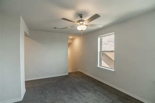 an empty room with windows and fan