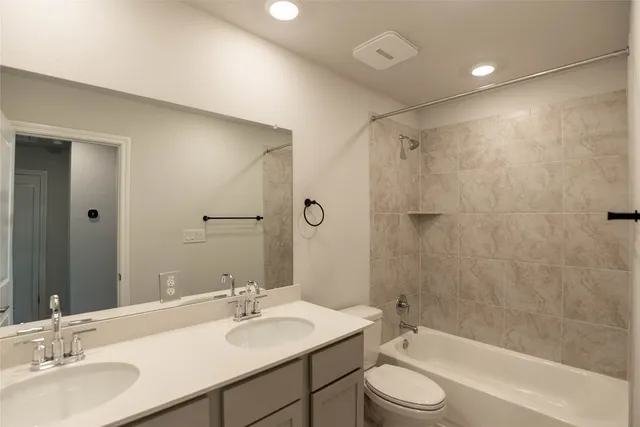 a bathroom with a granite countertop sink toilet a large mirror a shower and a bathtub