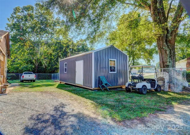 a view of backyard with small cabin and a wooden fence