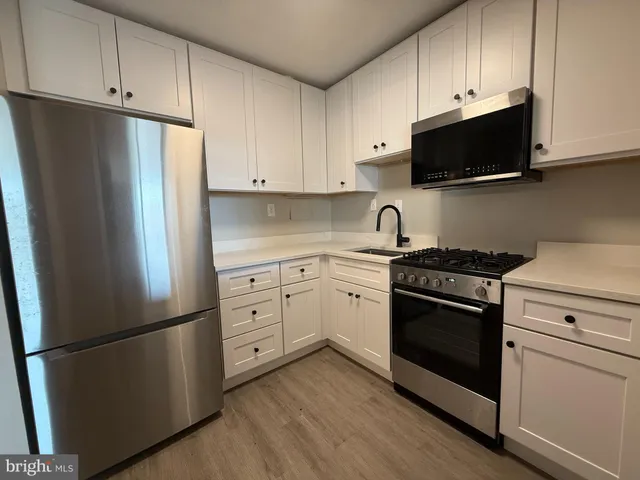 a kitchen with stainless steel appliances white cabinets granite counter tops and a refrigerator