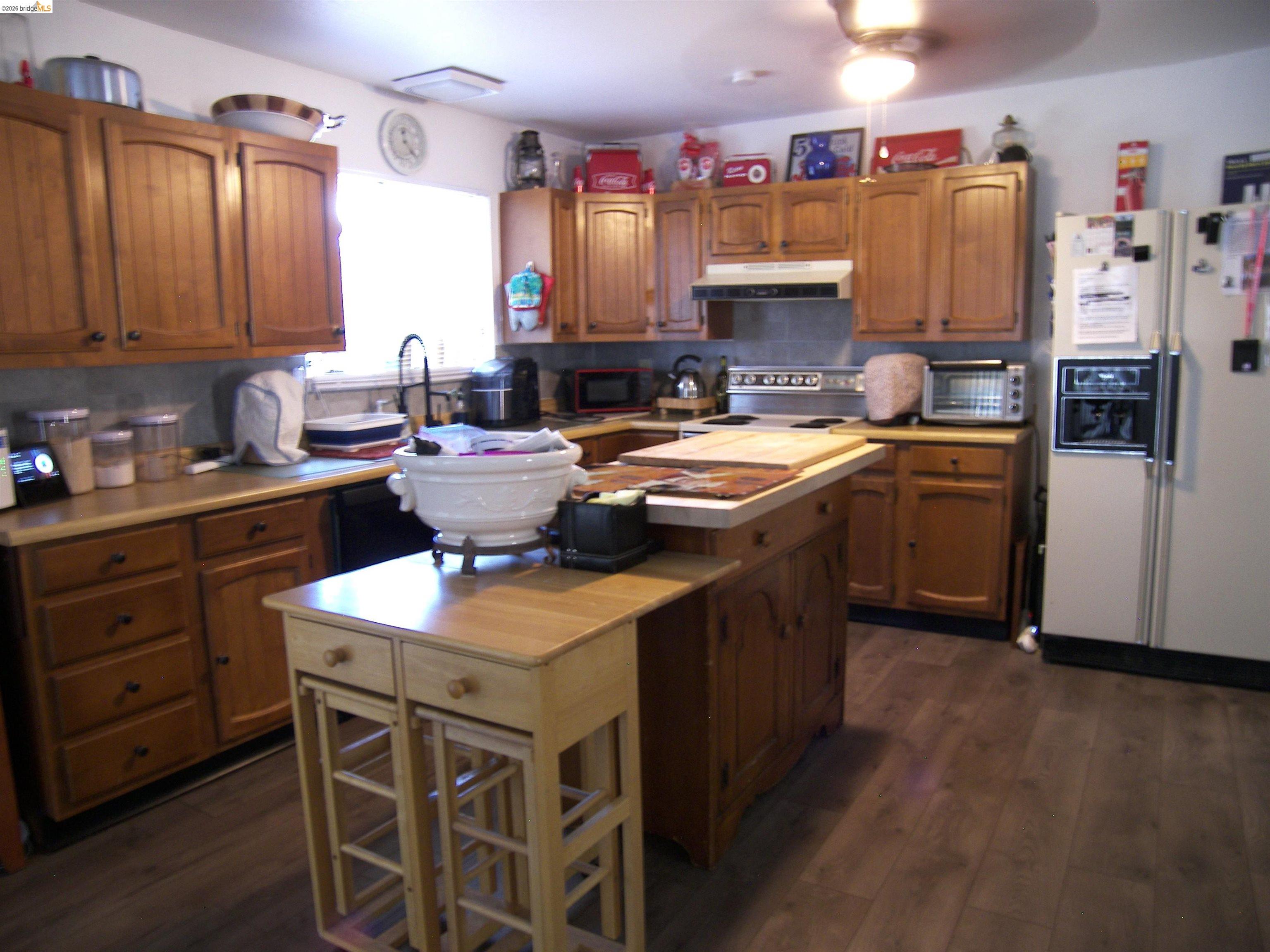 19215 Ferretti Road Groveland, CA 95321 - Photo 9 of 40 Kitchen featuring wood-finish flooring, wood cabinetry, a center island with bar seating, a built-in electric range with overhead ventilation, and a double-basin sink with a gooseneck faucet