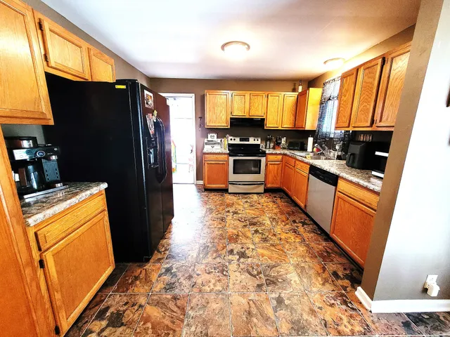 a large kitchen with stainless steel appliances a refrigerator a stove a sink dishwasher and wooden cabinets