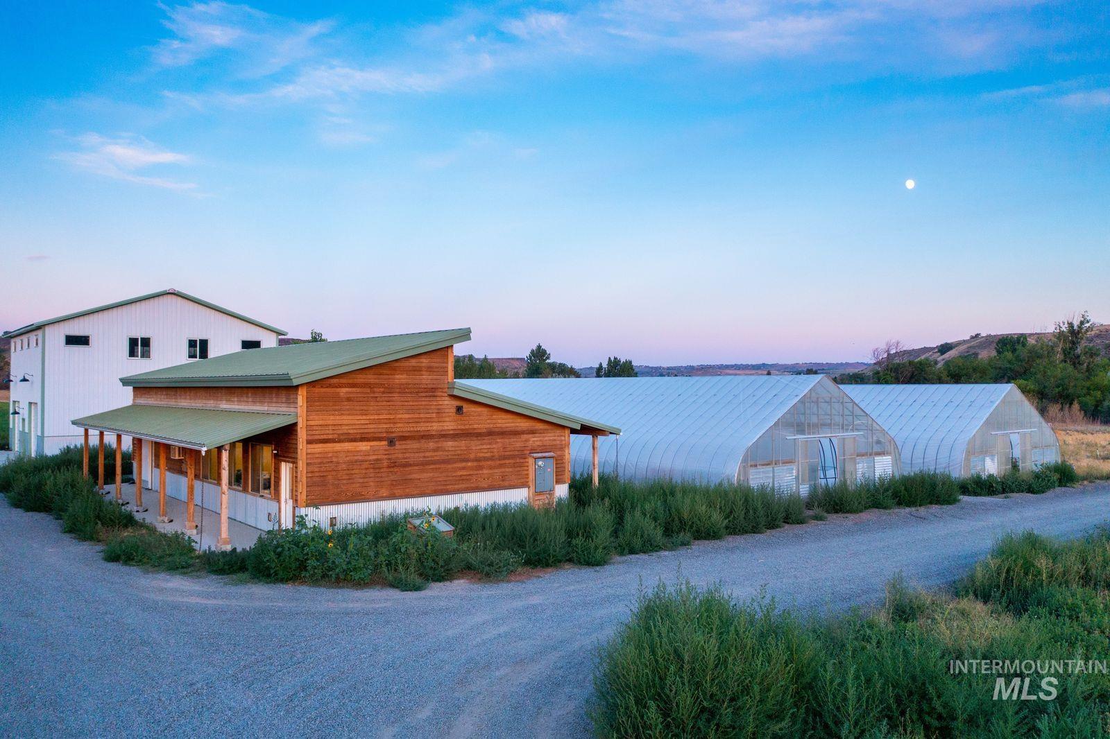Property exterior at dusk featuring an outbuilding, a greenhouse, covered porch, and a metal roof
