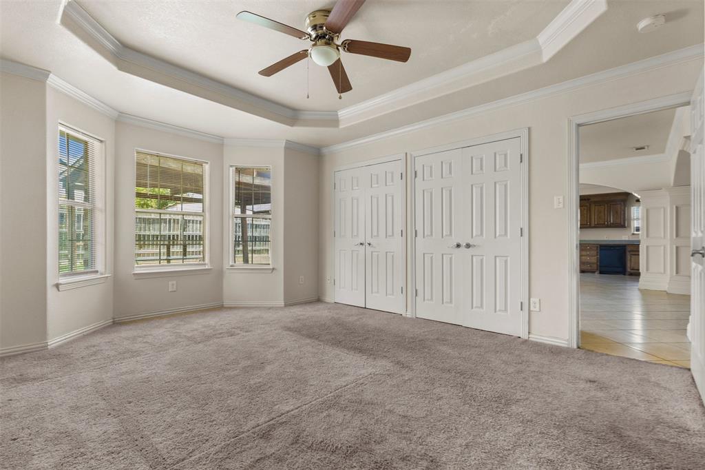 490 Lynne Drive Rockwall, TX 75032 - Photo 14 of 27 Unfurnished bedroom with a raised ceiling, multiple closets, arched walkways, carpet, and crown molding
