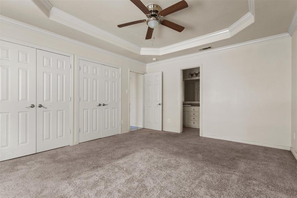 490 Lynne Drive Rockwall, TX 75032 - Photo 15 of 27 Unfurnished bedroom with a tray ceiling, multiple closets, ensuite bath, carpet, and crown molding