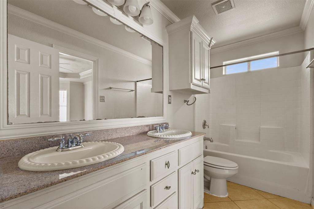 490 Lynne Drive Rockwall, TX 75032 - Photo 16 of 27 Full bathroom with ornamental molding, washtub / shower combination, light tile patterned floors, double vanity, and a textured ceiling