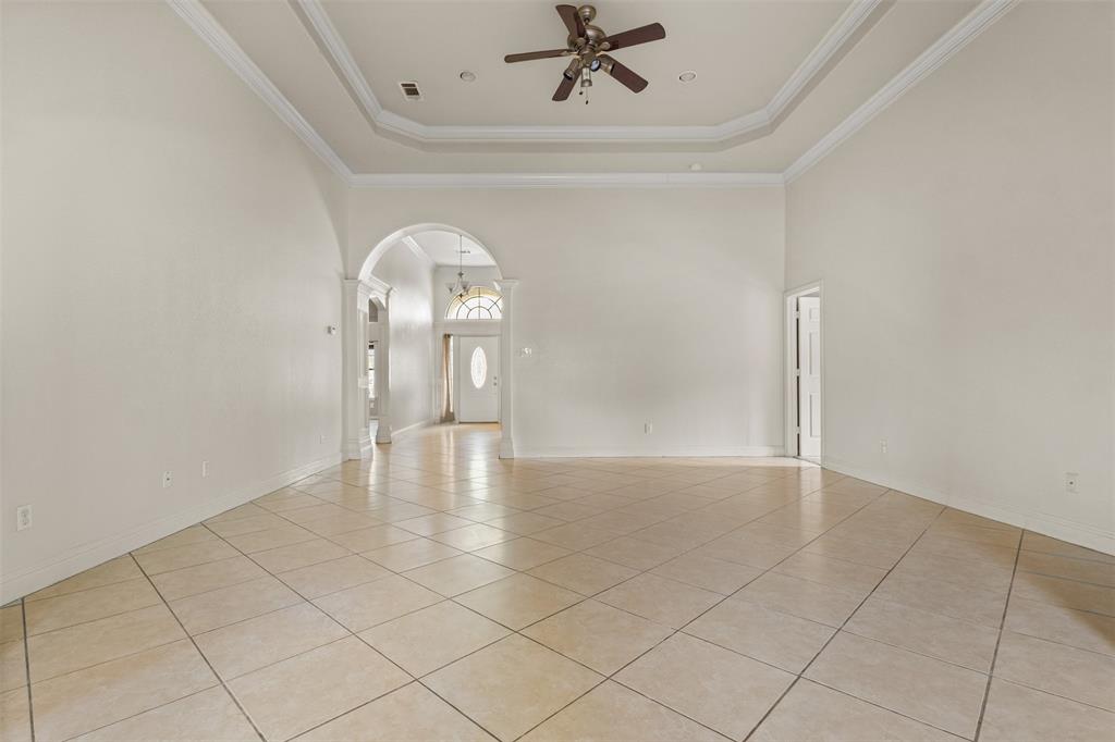 490 Lynne Drive Rockwall, TX 75032 - Photo 4 of 27 Unfurnished room featuring light tile patterned floors, a raised ceiling, a high ceiling, crown molding, and arched walkways