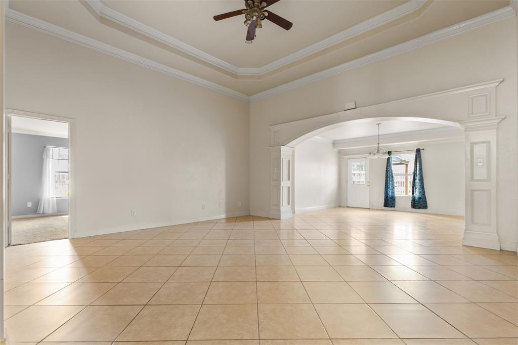 490 Lynne Drive Rockwall, TX 75032 - Photo 5 of 27 Unfurnished room featuring ornamental molding, a raised ceiling, light tile patterned flooring, arched walkways, and ceiling fan