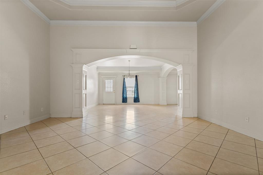 490 Lynne Drive Rockwall, TX 75032 - Photo 6 of 27 Spare room featuring arched walkways, a tray ceiling, light tile patterned flooring, ornamental molding, and ornate columns