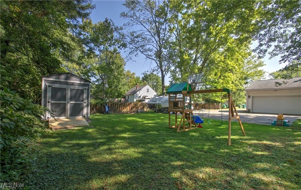 7368 Hopkins Road Mentor, OH 44060 - Photo 32 of 37 View of yard featuring a storage unit, fence, an outdoor structure, and a playground